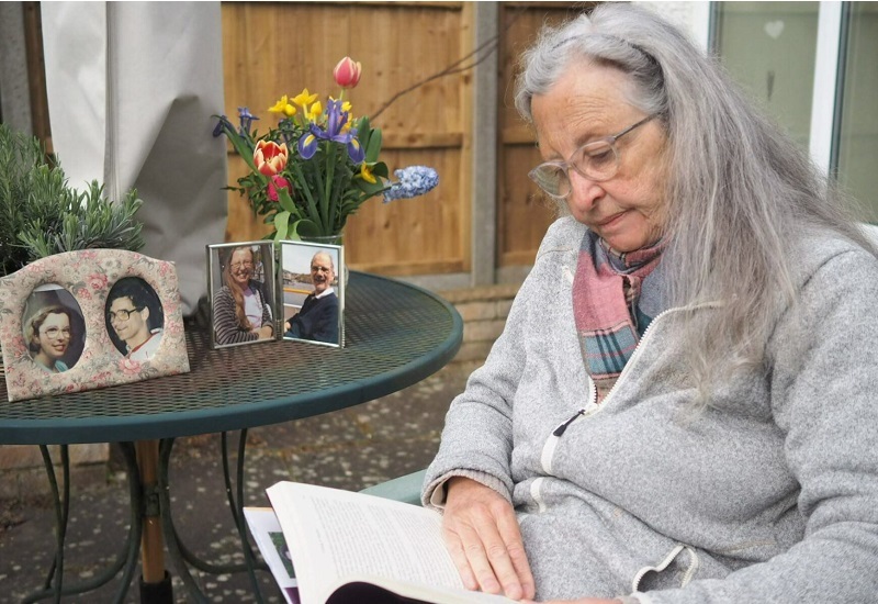 corinne-reads-book-with-photos-of-her-and-david-in-background