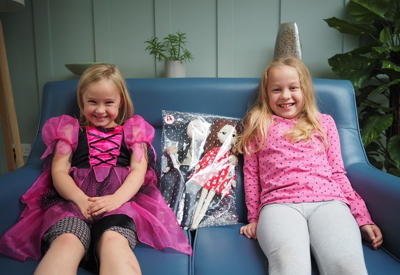 two-girls-sit-on-sofa-with-therapy-dolls-between-them