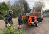 two-volunteers-load-trees-into-wood-chipper