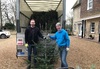 two-eh-crouch-staff-members-hold-christmas-tree-in-front-of-van