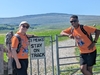 two-people-pose-next-to-a-sign-reading-3-peaks-stay-on-track