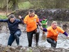 three-people-climb-out-of-the-water-onto-a-muddy-bank