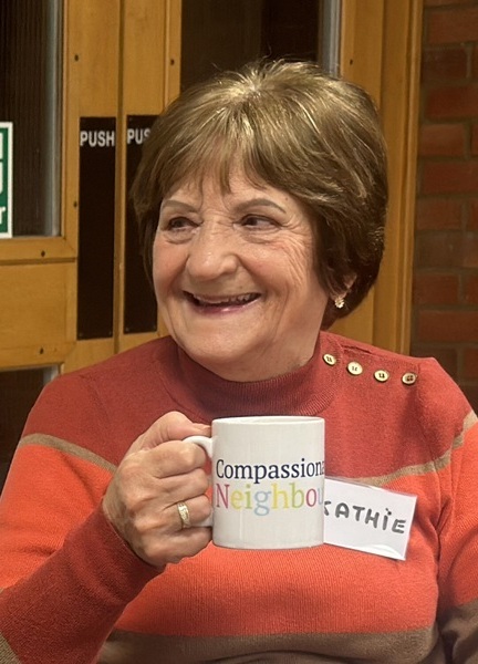 community-member-holding-up-a-hot-drink-and-smiling (cropped)