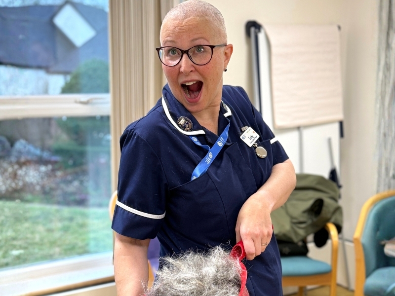 nurse-with-shaved-head-holds-up-hair-in-a-dustpan
