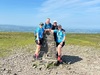 four-people-in-matching-blue-shirts-at-the-peak-of-a-mountain