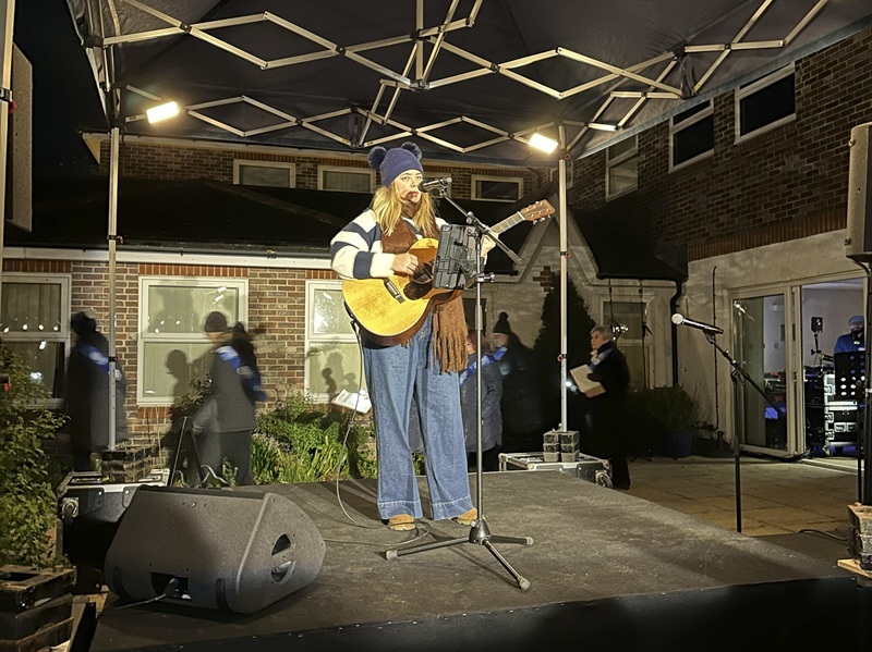 singer-standing-on-stage-outdoors-playing-acoustic-guitar