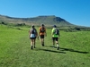 three-people-walking-away-from-the-camera-toward-a-mountain