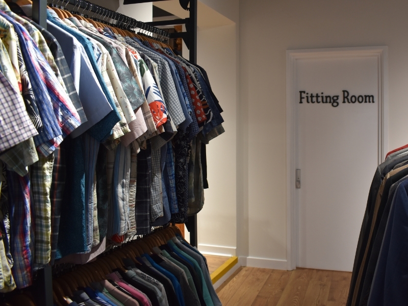 mens-shirts-hanging-on-clothes-rails-outside-a-door-reading-fitting-room
