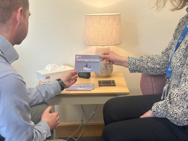two-people-holding-and-looking-at-family-support-services-postcard