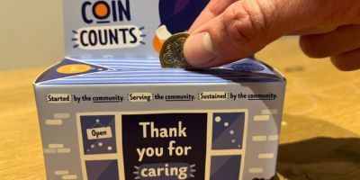 person-putting-pound-coin-into-homebox