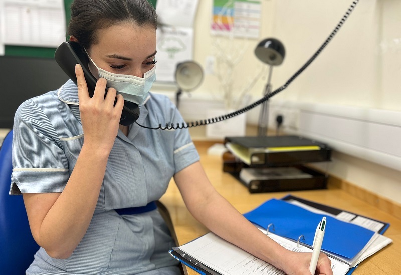 nurse-speaking-on-phone-while-taking-notes