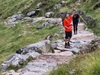 man-cheers-with-hiking-pole-in-the-air-as-he-walks-up-a-mountain-path
