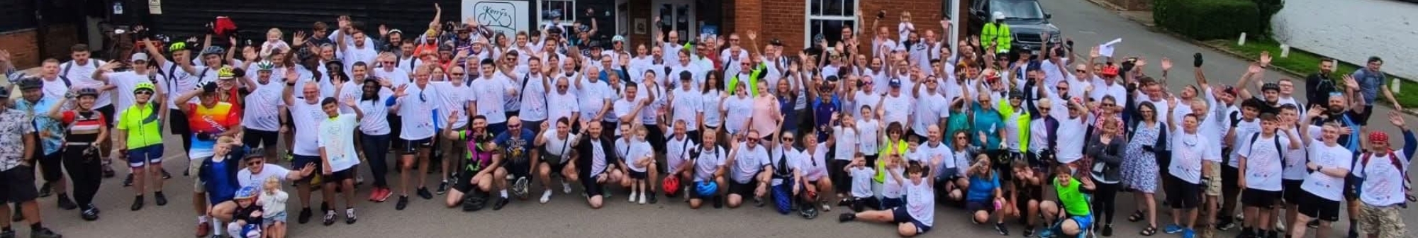 large-group-of-people-in-matching-shirts-waving-outside-a-pub