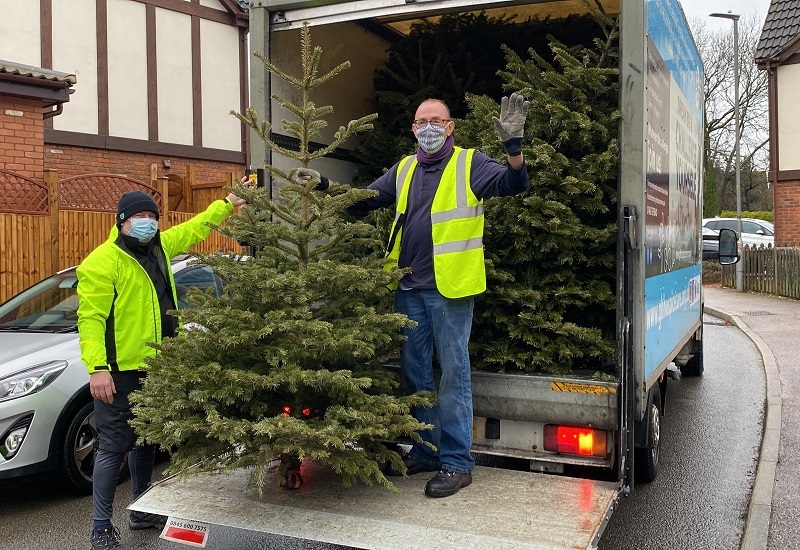 two-volunteers-on-back-of-hospice-van-holding-up-a-tree