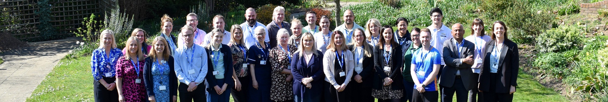 large-group-of-garden-house-hospice-care-staff-standing-in-the-garden-smiling