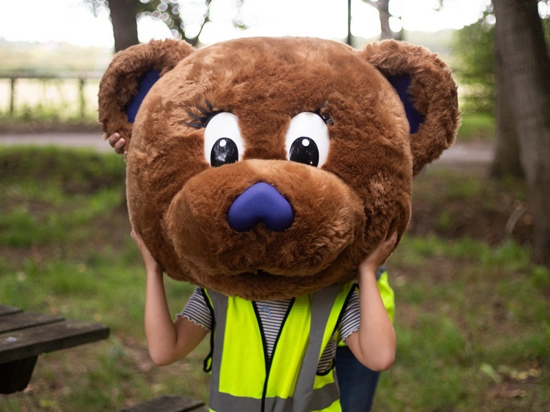 young-girl-in-high-vist-vest-wearing-bear-mascot-head