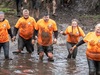 a-family-covered-in-mud-wade-through-the-water