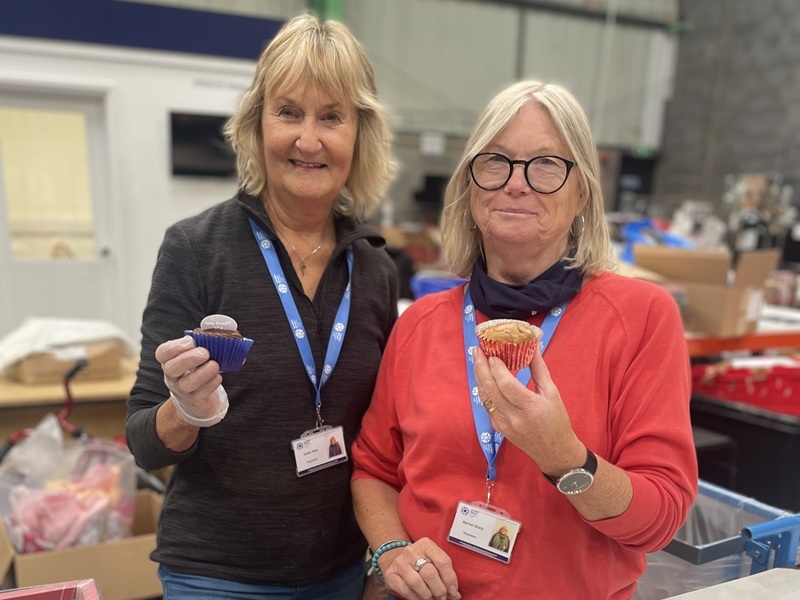 two-volunteers-at-the-depot-holding-up-cupcakes