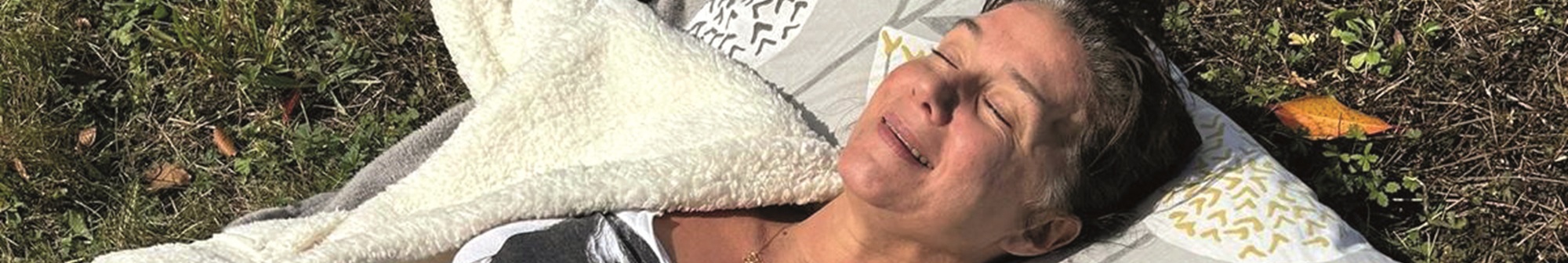 kelly-laying-on-pillows-on-the-grass-smiling