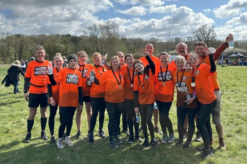 a-group-cheering-and-wearing-muddy-mayhem-medals-post-event
