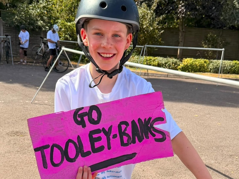 boy-wearing-bicycle-helmet-holding-sign-that-says-go-tooley-banks