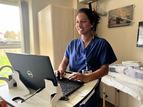 doctor-smiles-while-making-notes-in-patient-sideroom