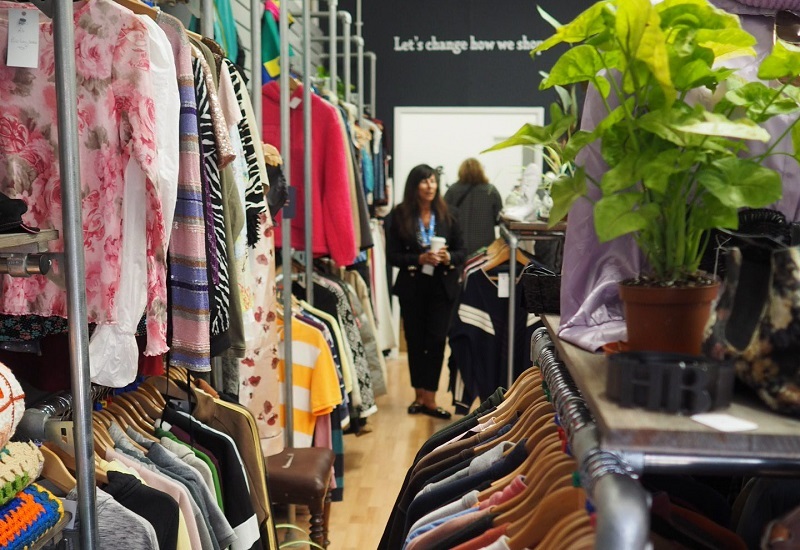 clothes-rails-in-shop-with-staff-member-in-the-background